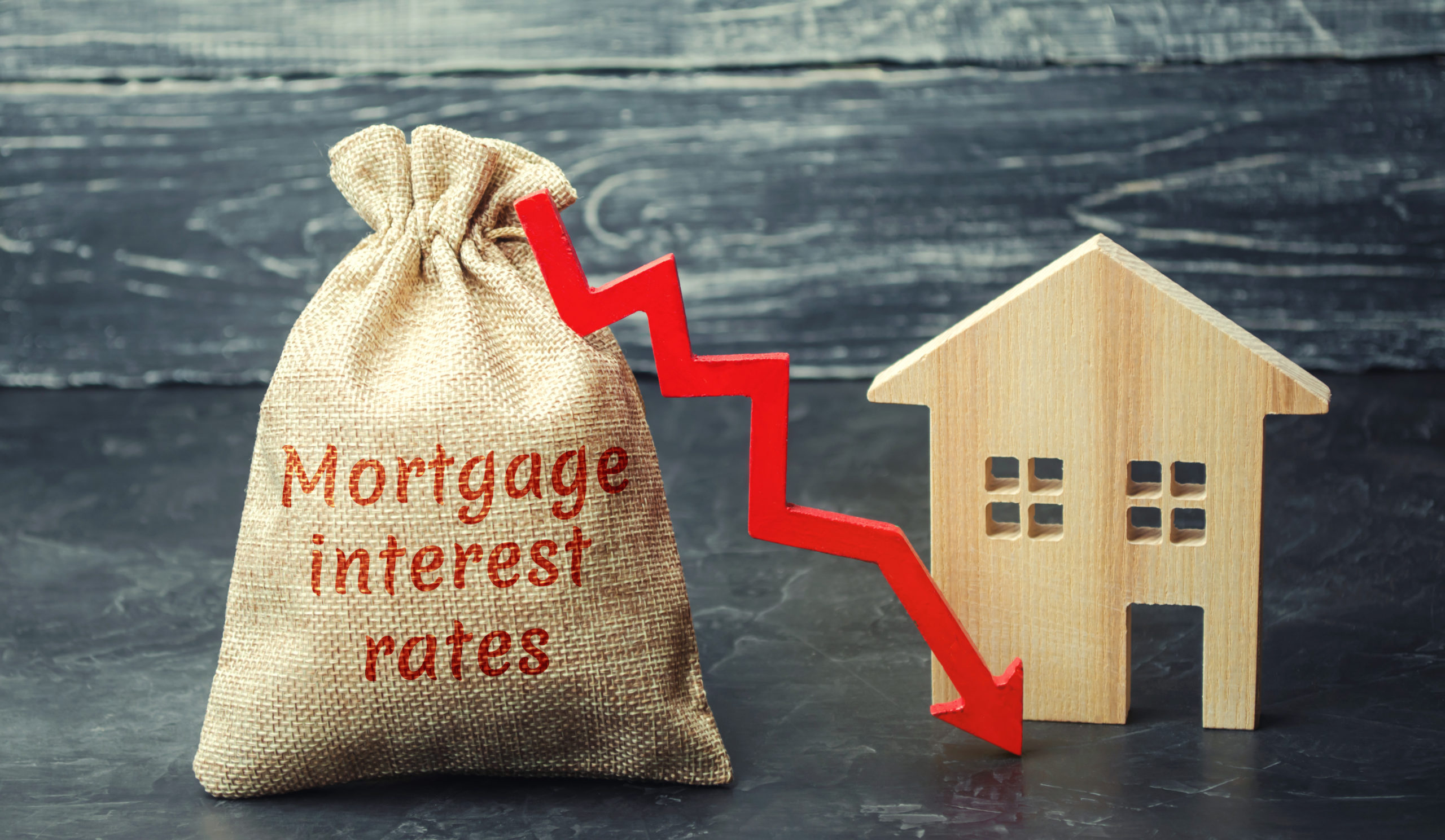 Bag with the money and the word Mortgage interest rates and arrow to down and house. Low interest in mortgages. Reducing interest payments for mortgages. The fall in housing rates on credit. Low housing demand